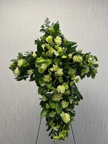 Standing cross on an easel in white blooms and green button chrysanthemums.