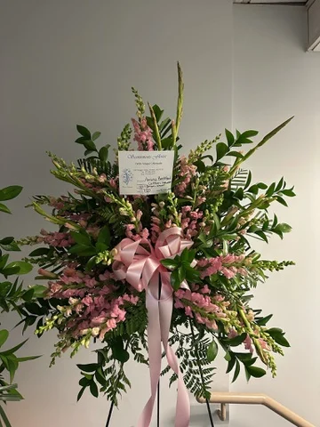 Standing spray on an easel in pink roses, alstroemeria and snapdragons with a pink ribbon.