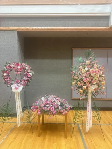 Two pink and white memorial pieces set up on easels inside a funeral home room.